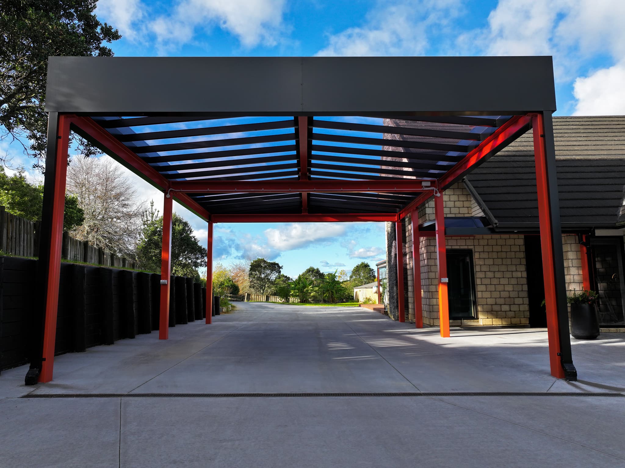 Front view of the Ardmore box-perimeter carport with red steel framing and acrylic roofing