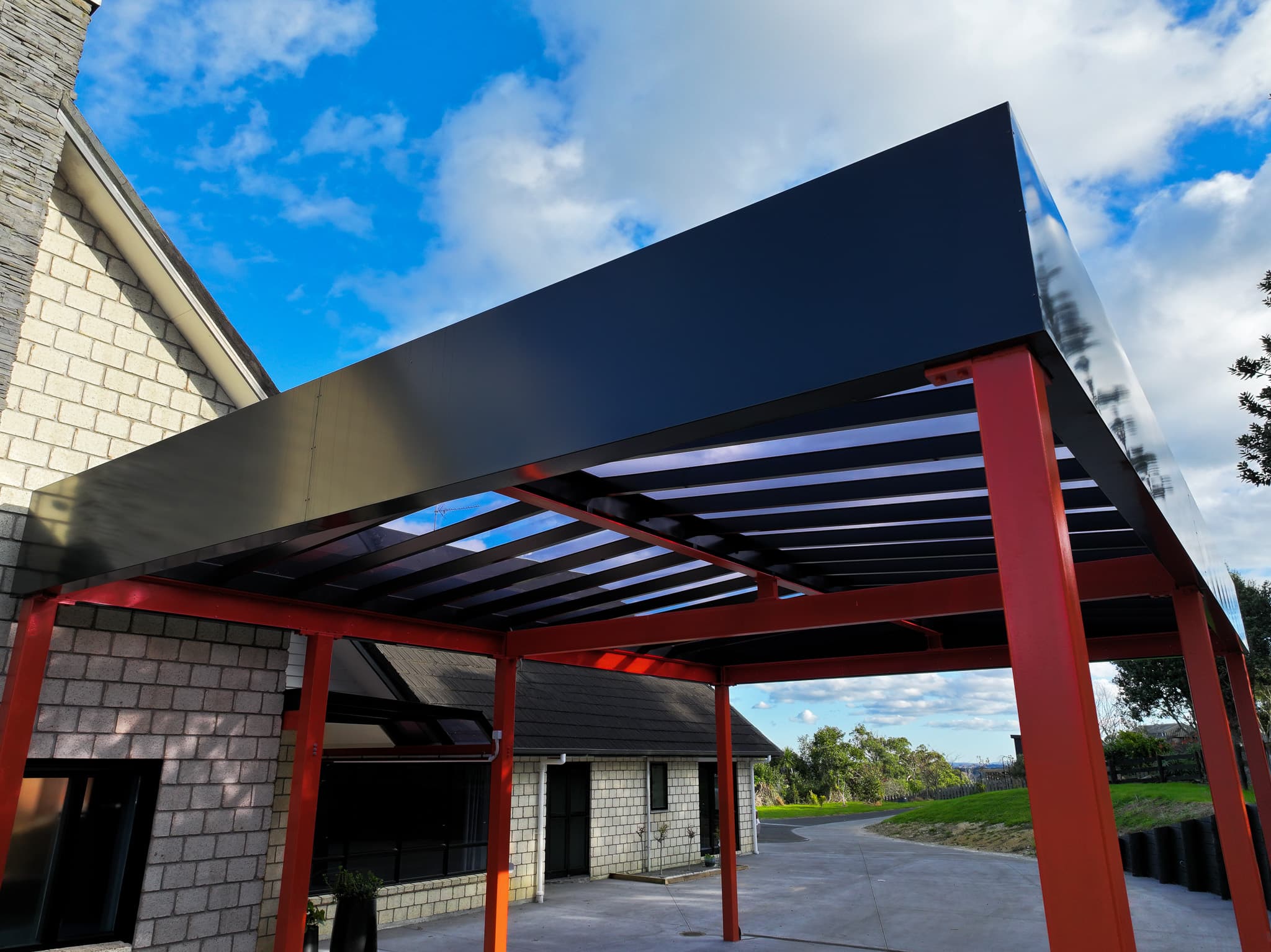 Side view of the Ardmore carport showing the black perimeter fascia and red steel posts