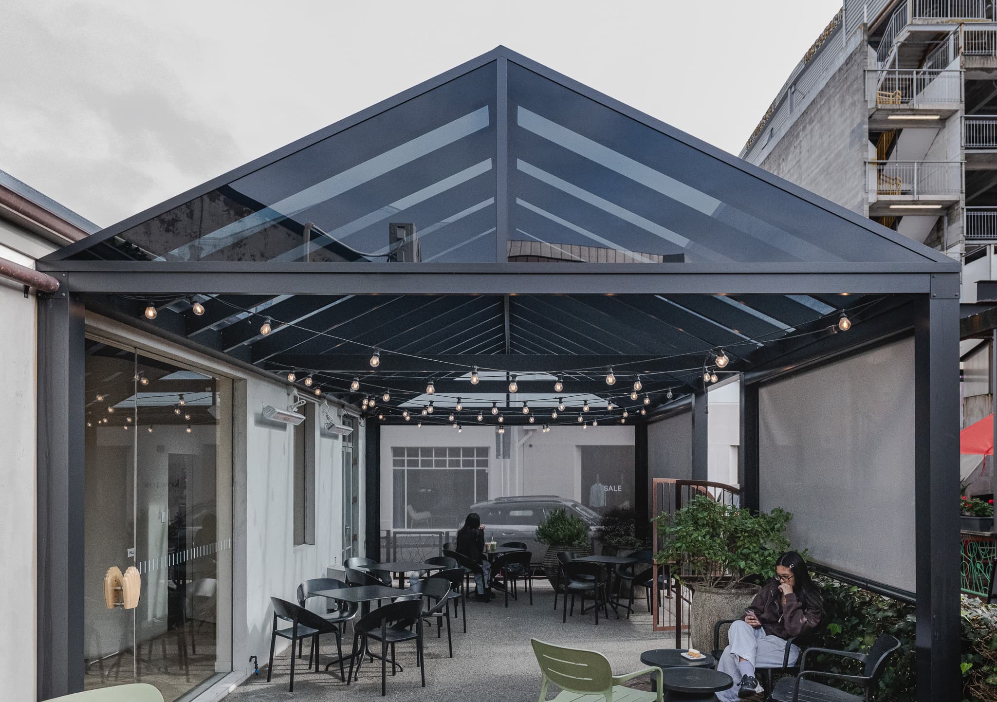 Front-on view of the dark-tint acrylic gable canopy over outdoor seating at Atelier Shu Cafe in Newmarket
