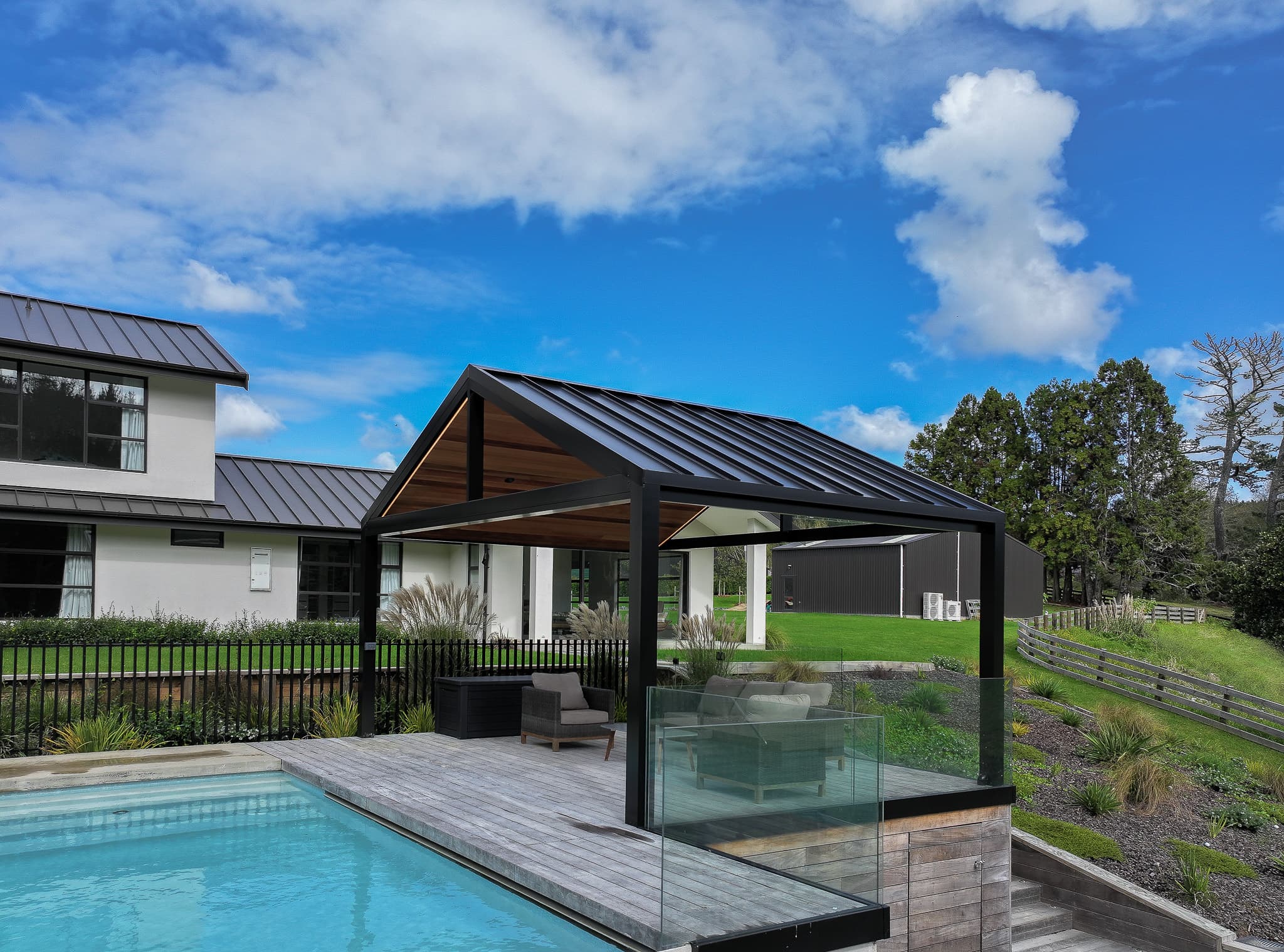 Custom black gable pergola beside a pool and Auckland home