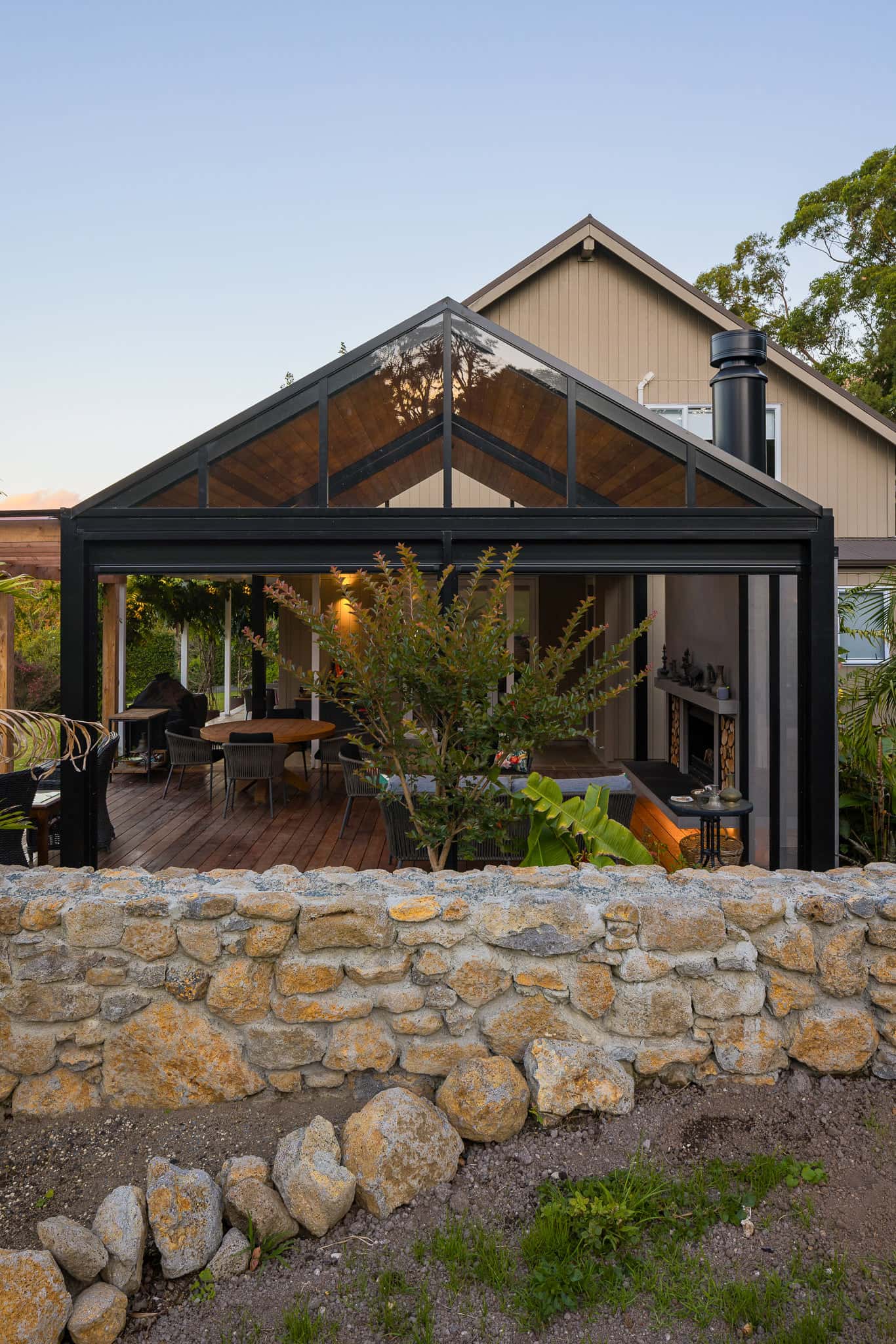 Freestanding matte black gable outdoor room beside a Warkworth home