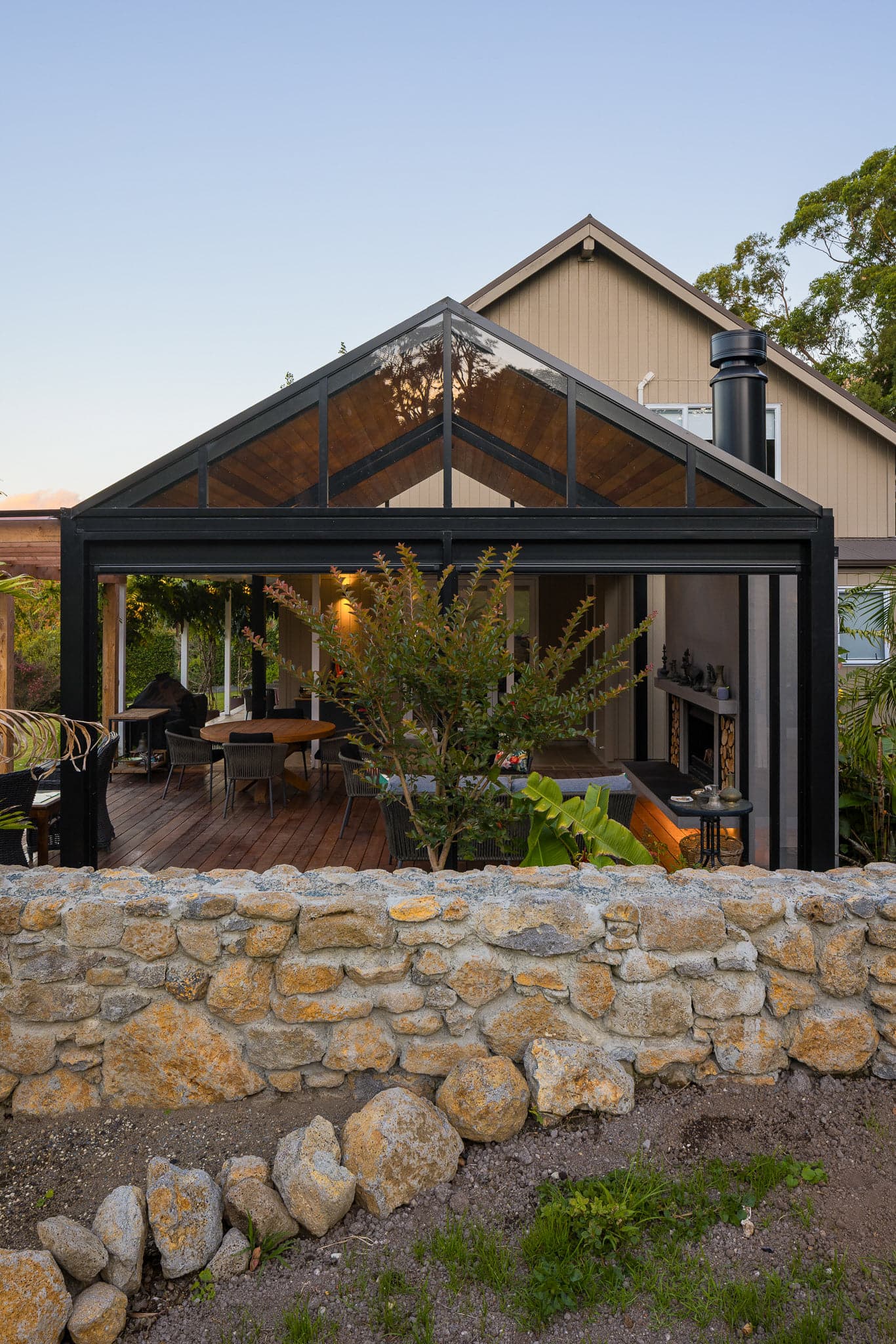 Freestanding matte black gable outdoor room beside a Warkworth home