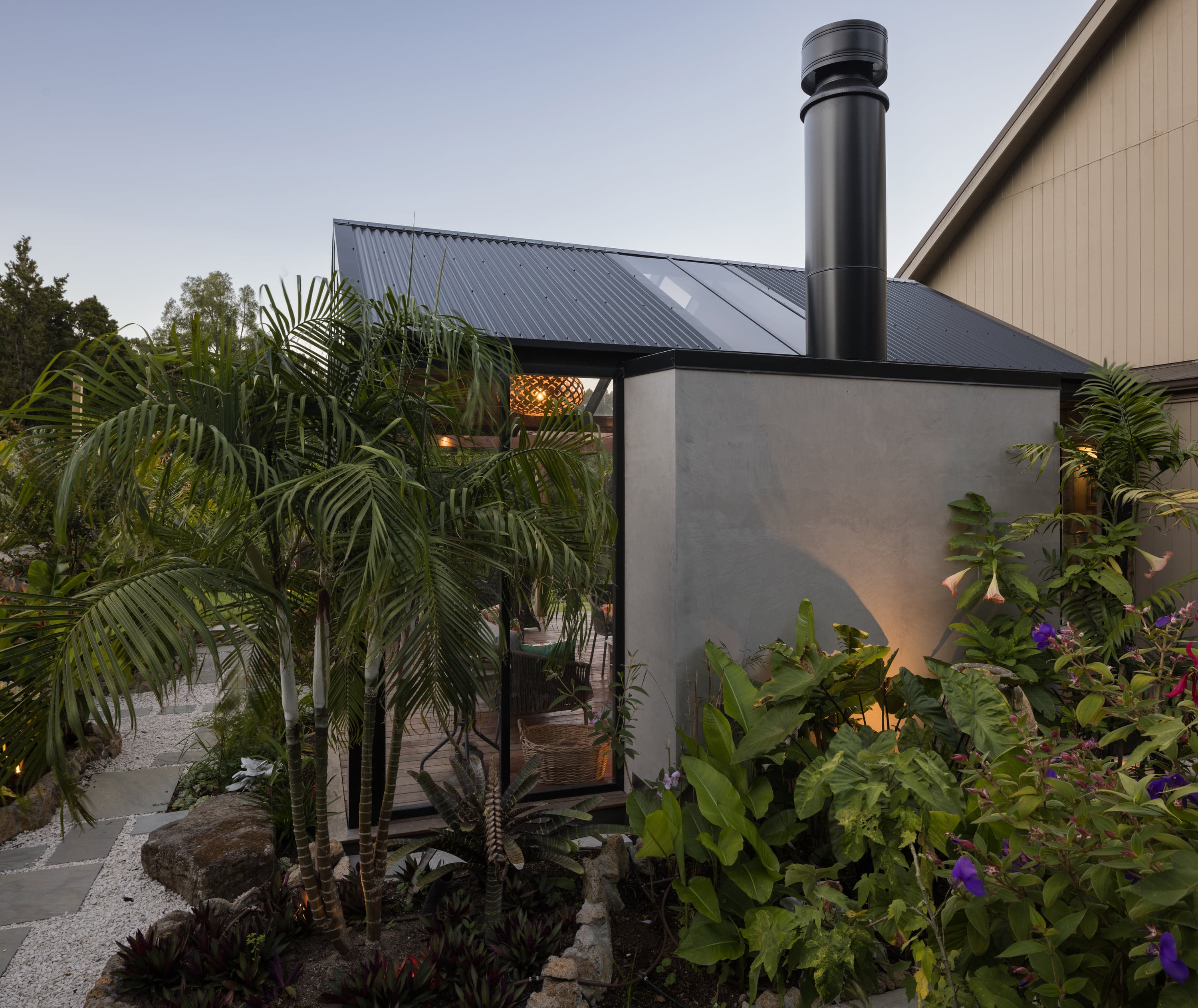 Garden-side exterior view with the fireplace chimney and matte black roof