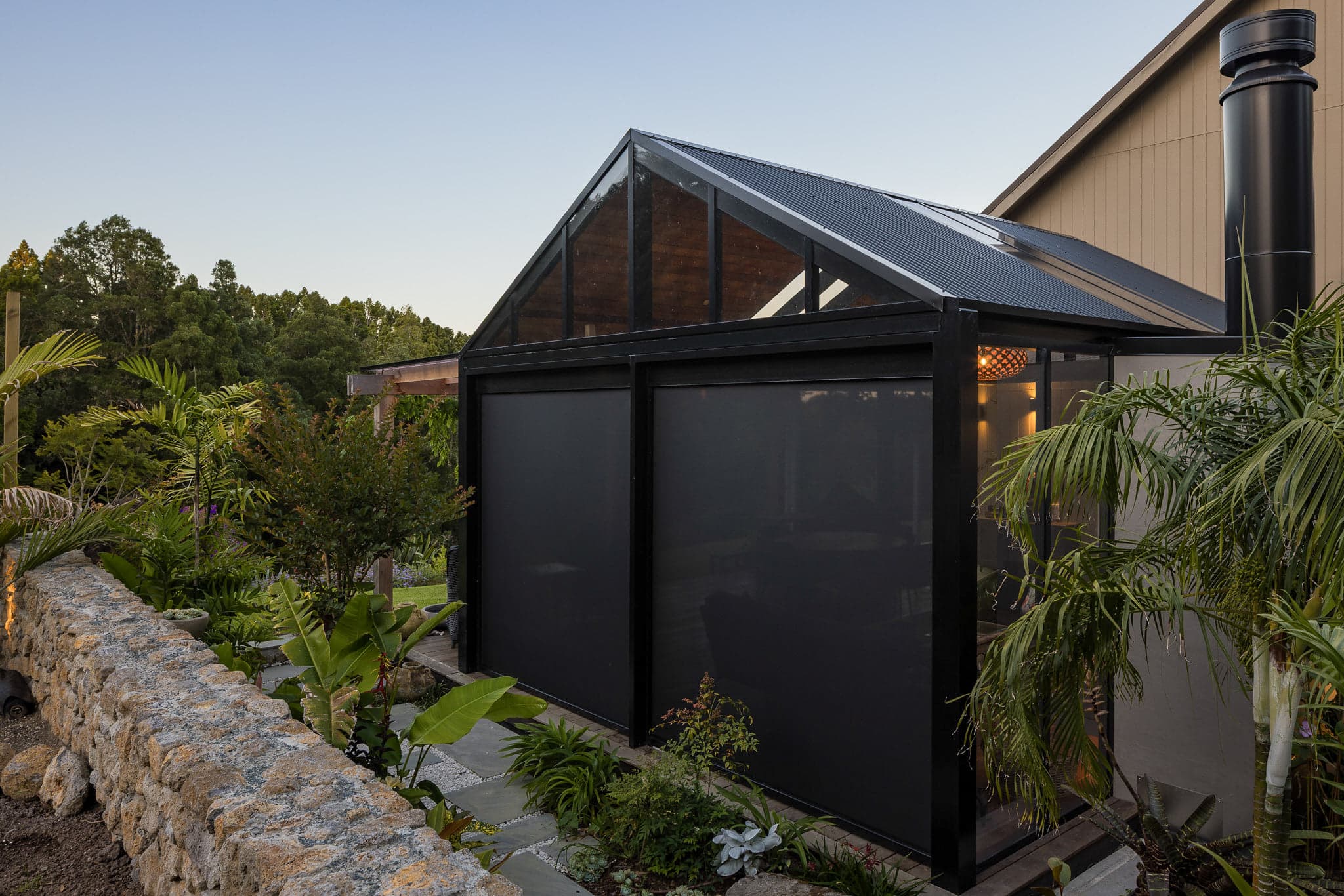 Exterior view of the Warkworth outdoor room with screens and planting