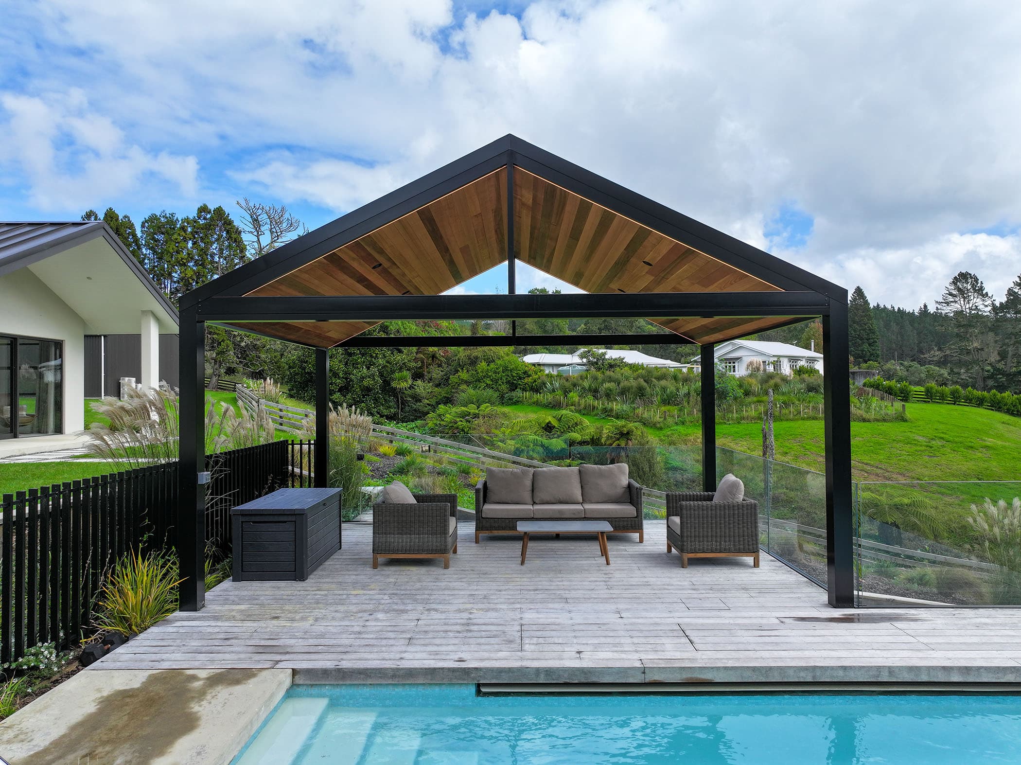 Riverhead gable pergola with timber ceiling overlooking a green landscape and pool