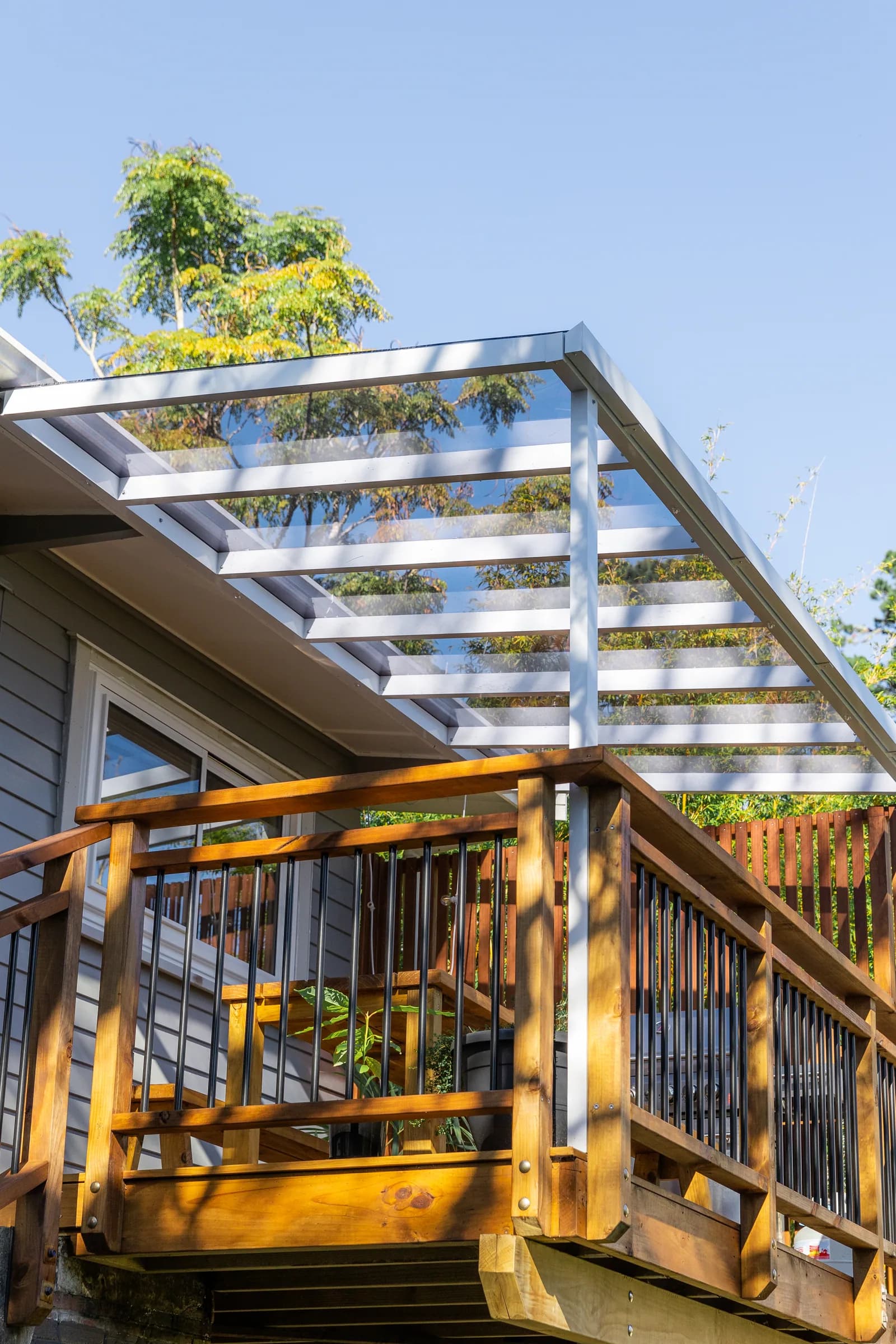 White pitched acrylic pergola attached above an elevated timber deck